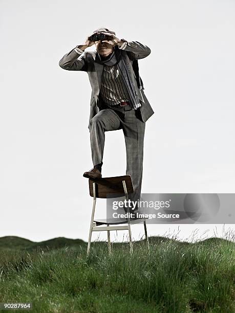 man in chair with binoculars - standing on chair stockfoto's en -beelden