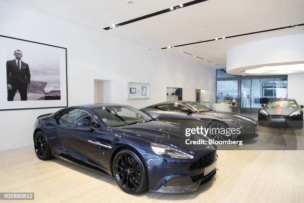 Framed photograph of actor Daniel Craig in his role as James Bond 007, hangs above Aston Martin automobiles, left, Vanquish, centre, DB11 and Rapide...
