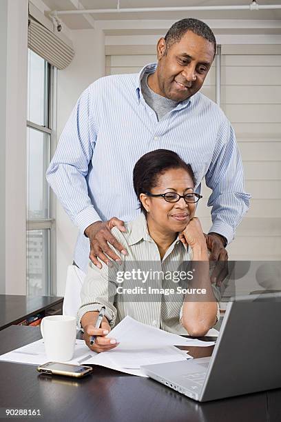 couple doing home finances - couple 50 55 laptop stock-fotos und bilder