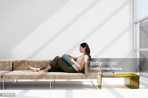 woman reading on a sofa - woman home sit foto e immagini stock