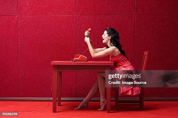 woman in red room with telephone - angry woman red stock pictures, royalty-free photos & images