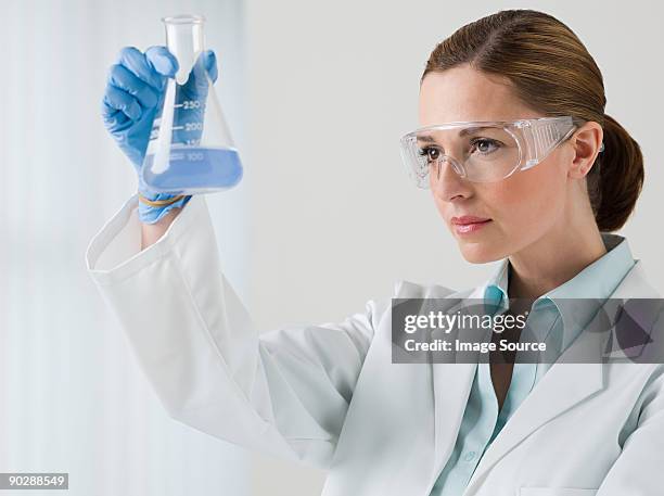 female scientist holding a flask - pallone di vetro foto e immagini stock