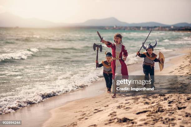 los niños vikingos carga thrrough la playa - vikingo fotografías e imágenes de stock