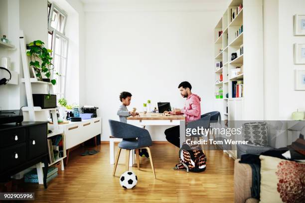 young boy and father playing game together at home - ball on a table stockfoto's en -beelden