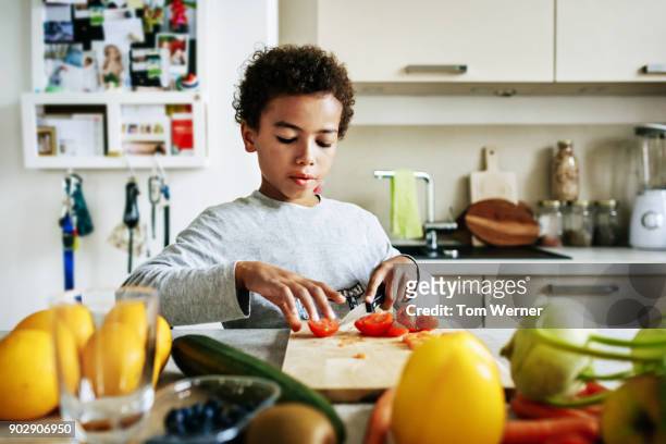 young boy helping to prepare lunch at home - boy kitchen stockfoto's en -beelden