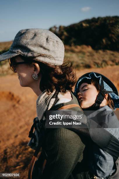 child sleeping on mother's back while hiking - babytrage stock-fotos und bilder