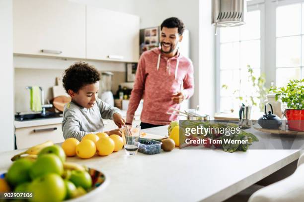 young boy helping his dad prepare lunch - tom hale stock pictures, royalty-free photos & images