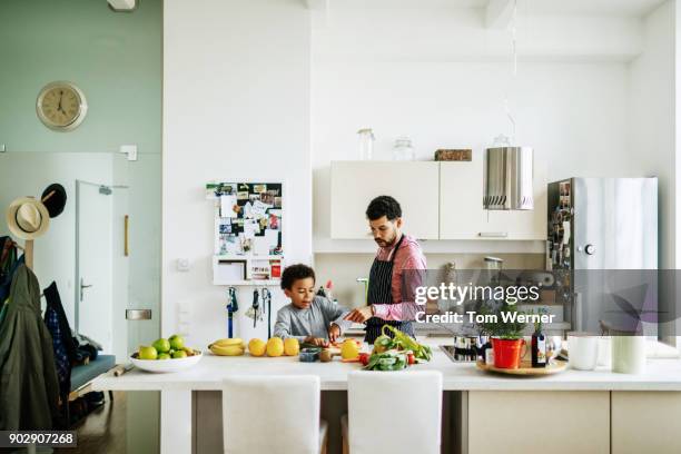 father and son helping each other prepare some lunch - family at kitchen fotografías e imágenes de stock