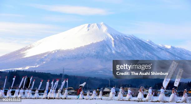 People wearing white clothes holding three-meter-long 'Kenzao' rods march on at the skirt of Mount Iwatesan during the Hirakasa Hadaka Mairi on...