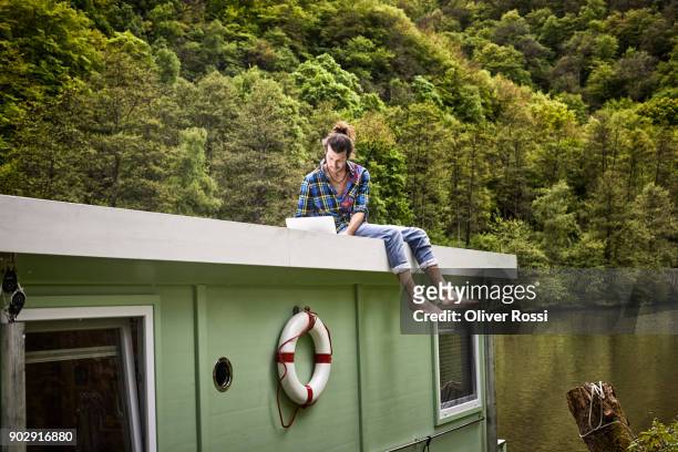 man using laptop on a houseboat - adventure stock-fotos und bilder