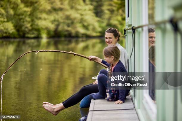 mother and daughter on a houseboat with girl using stick as fishing rod - creative fishing stock pictures, royalty-free photos & images