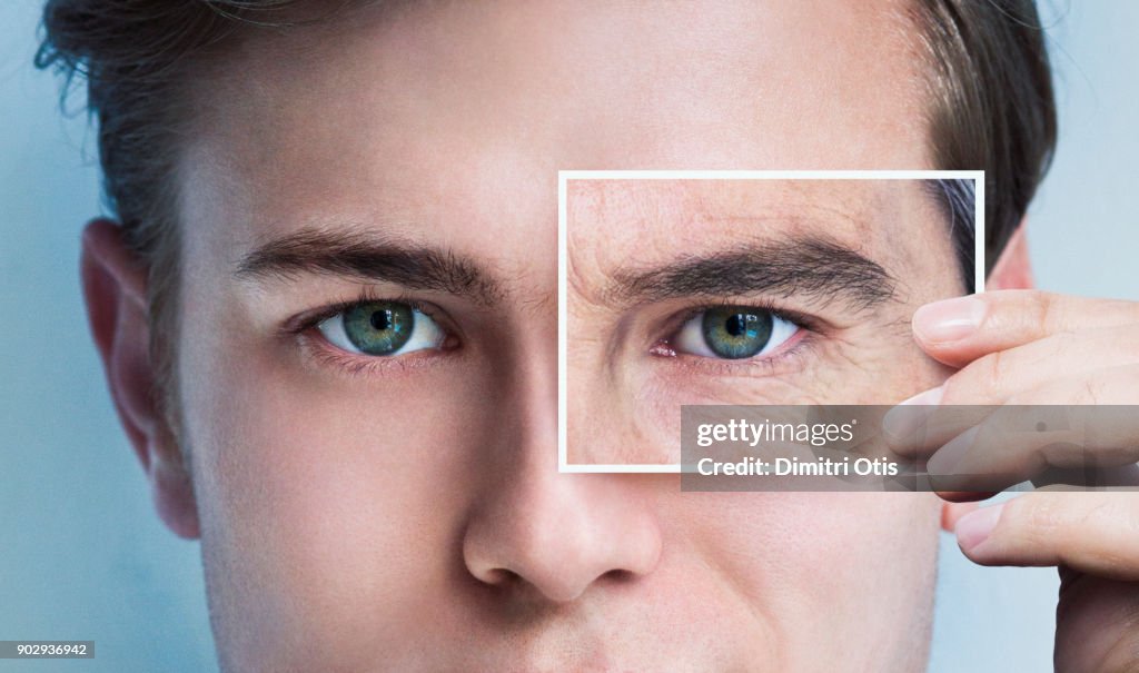 Young man's eyes covered by picture of aged eye