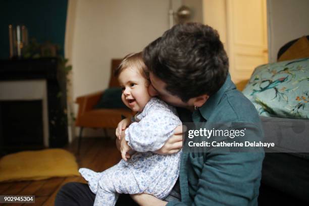 a 1 year old baby girl in the arms of her dad at home - 2 year old blonde girl father stock-fotos und bilder