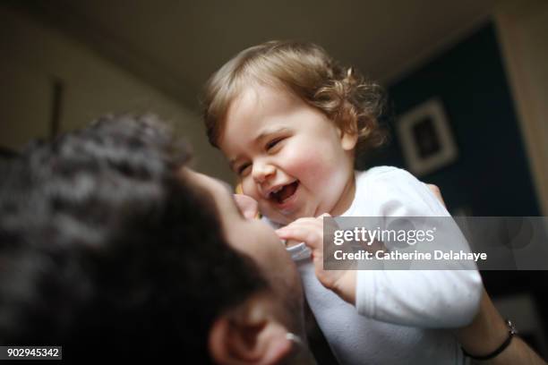 a 1 year old baby girl in the arms of her dad at home - 2 year old blonde girl father ストックフォトと画像