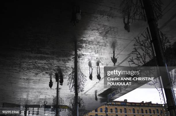 People walk under mirror panels designed by British architect Norma Foster at the Old Harbour of Marseille, southern France, on January 9, 2018. /...