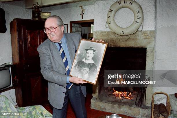 France's far-righter candidate to the upcoming presidential election Jean Marie Le Pen poses 30 March 1995, with a photograph of his father who was a...