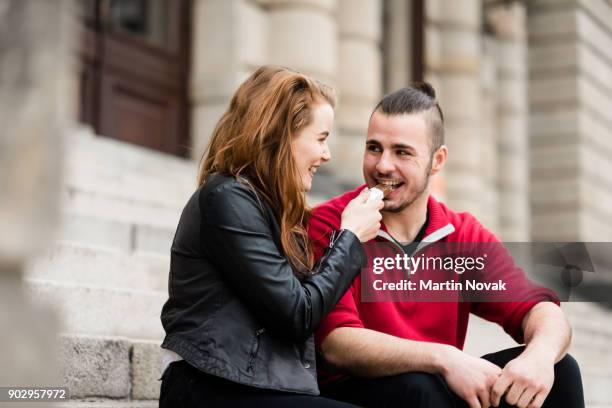 smiling woman making her man eat chocolate - couple chocolate - fotografias e filmes do acervo