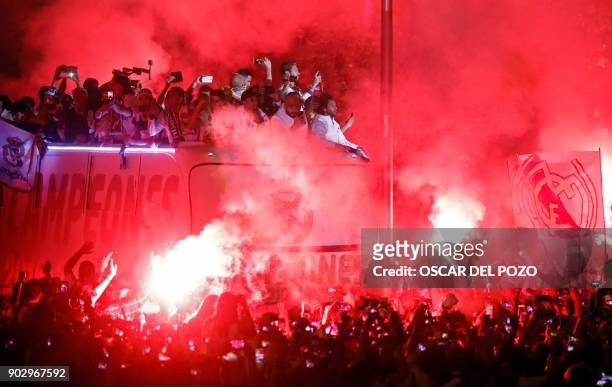 Real Madrid football team fans surround the bus as Real Madrid players hold up the trophy celebrating the team's win on Plaza Cibeles in Madrid on...