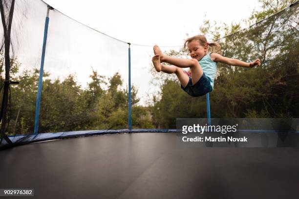 cheerful kid playing on trampoline in the backyard - trampoline photos et images de collection