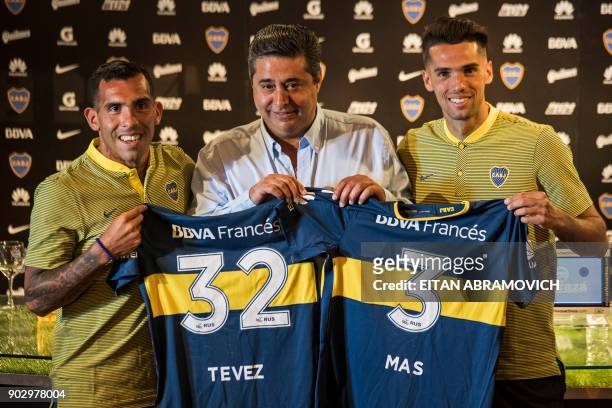 Boca Juniors' newly returned player Carlos Tevez and newly signed footballer Emmanuel Mas pose with their new jerseys next to Boca Juniors'...