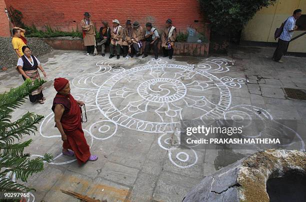 Tibetans-in-exile sit by a ritual drawing during a ceremony to mark the 49th Tibetan Democracy Day at the Boudhanath Stupa in Kathmandu on September...