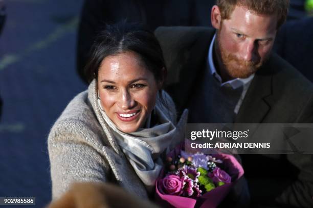 Britain's Prince Harry and fiancée US actress Meghan Markle meet well-wishers as they leave after a visit to Reprezent 107.3FM community radio...