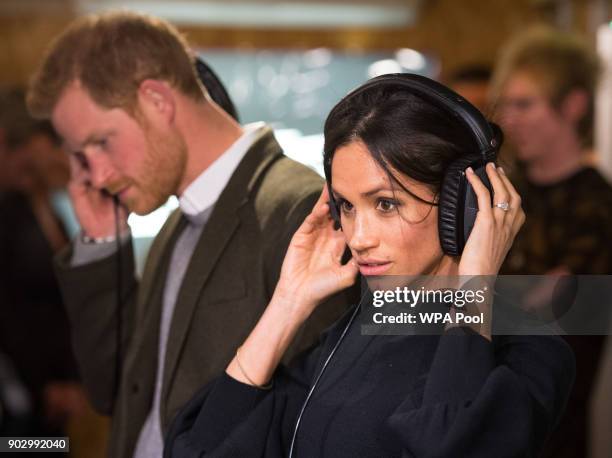 Prince Harry and Meghan Markle listen to a broadcast through headphones at Reprezent 107.3FM in Pop Brixton on January 9, 2018 in London, England....