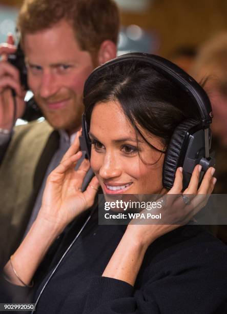 Prince Harry and Meghan Markle listen to a broadcast through headphones at Reprezent 107.3FM in Pop Brixton on January 9, 2018 in London, England....