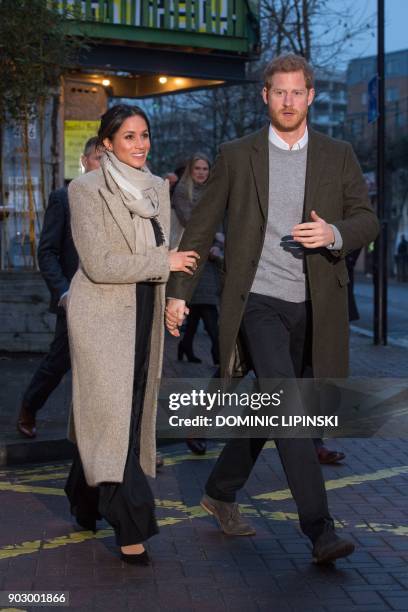 Britain's Prince Harry and his fiancée, US actress Meghan Markle walk out to meet well-wishers as they leave after a visit to Reprezent 107.3FM...