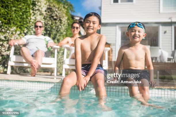 brothers sitting near the swimming pool and looking at camera - family with two children stock pictures, royalty-free photos & images