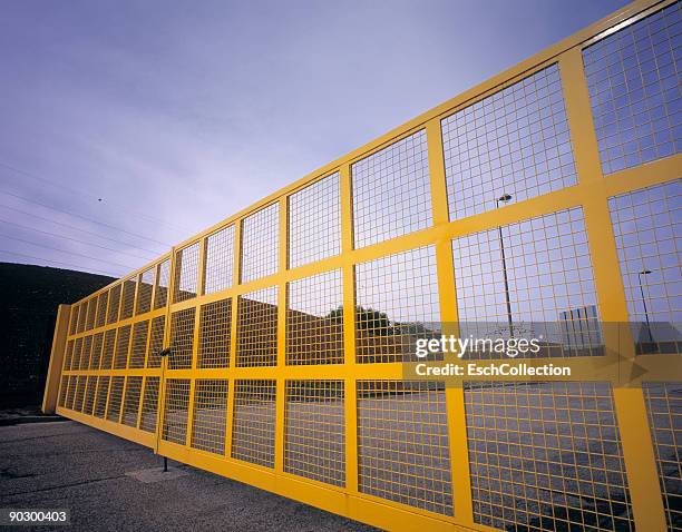 large yellow wire fence catching morning sunlight. - rete metallica foto e immagini stock