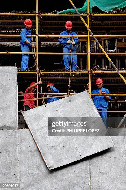 Chinese workers disassemble a scaffolding in Shanghai on August 11, 2009. China's economy, the world's third-largest, has taken a heavy hit from the...