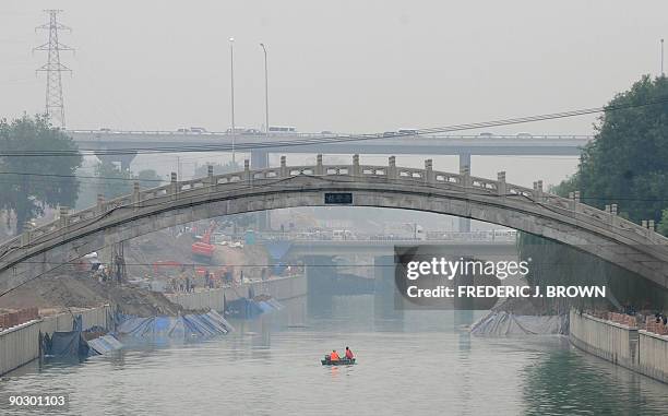 Workers in a boat cruise along a canal on a hazy day in Beijing on August 18, 2009. China could see its greenhouse gas emissions peak in 2030 if it...