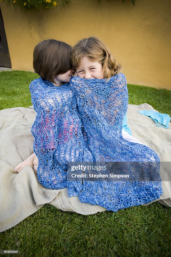 Two girls sharing secret in shawl