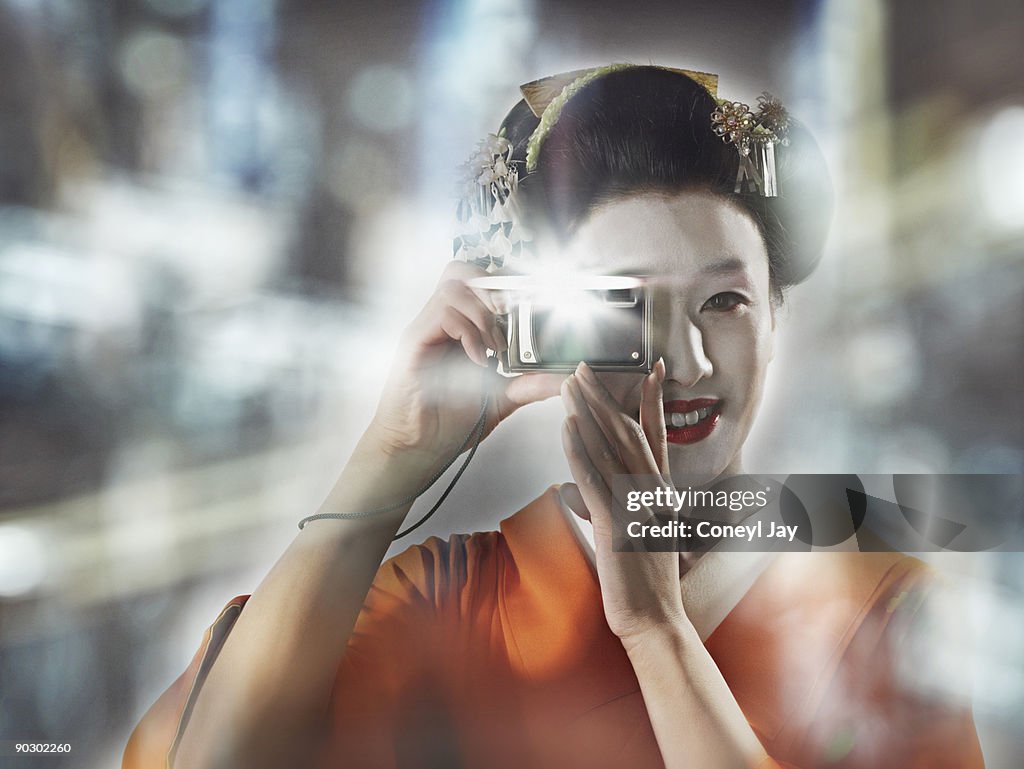 Geisha taking a photo with her digital camera outd