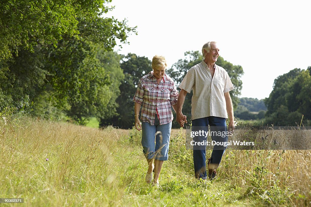 Elderly couple walking in countryside.