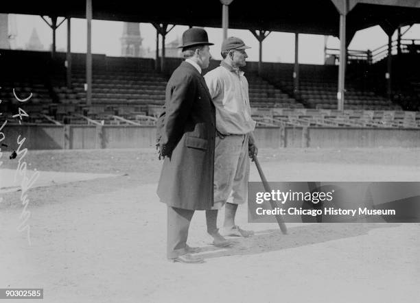 American baseball player Honus Wagner of the Pittsburgh Pirates stands with a man identified as Dr. C. W. Harrison on the field at West Side Grounds,...