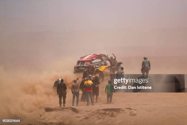 Fans cheer as Orlando Terranova of Argentina and Mini X-Raid and his co-driver Bernardo Graue of Argentina free their Mini John Cooper Rally Works...