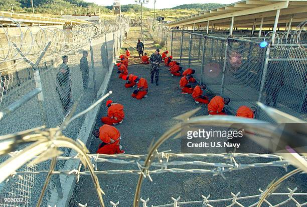 In this handout photo provided by the U.S. Navy, U.S. Military Police guard Taliban and al Qaeda detainees in orange jumpsuits January 11, 2002 in a...