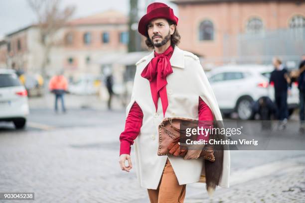 Guest wearing cape, red hat is seen during the 93. Pitti Immagine Uomo at Fortezza Da Basso on January 9, 2018 in Florence, Italy.