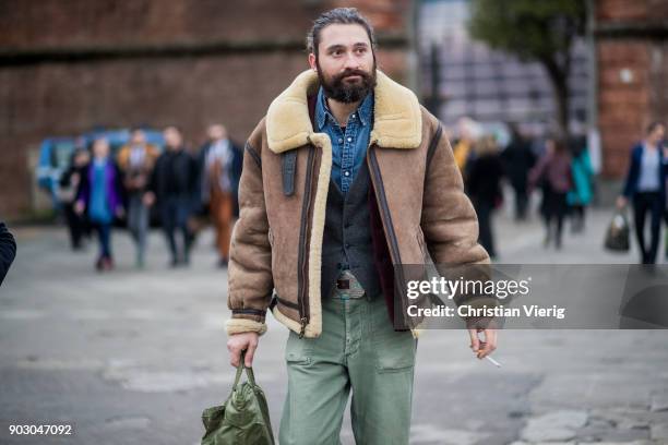 Guest wearing shearling jacket, olive pants is seen during the 93. Pitti Immagine Uomo at Fortezza Da Basso on January 9, 2018 in Florence, Italy.