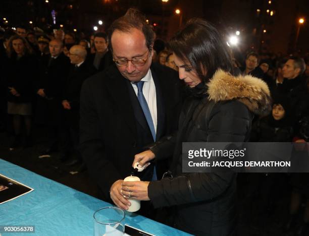 Former French president Francois Hollande and the widow of one of the victims light a candle during a gathering organized by the CRIF outside the...