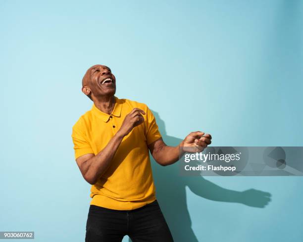 portrait of a mature man dancing, smiling and having fun - senior studio portrait stock-fotos und bilder