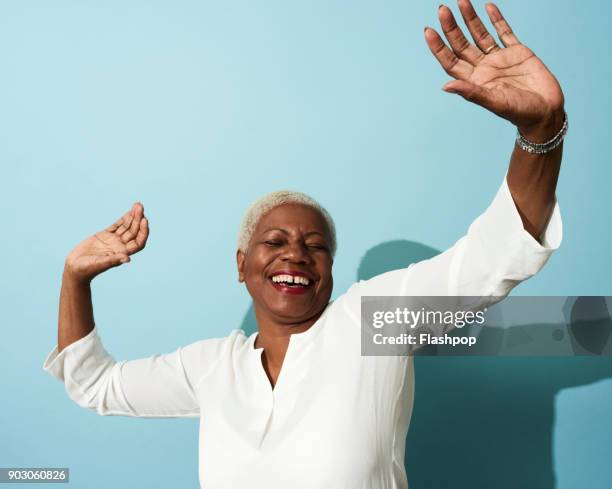 portrait of mature woman dancing, smiling and having fun - woman on coloured background stock pictures, royalty-free photos & images