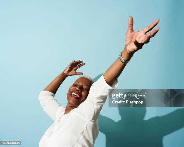 portrait of mature woman dancing, smiling and having fun - braccia alzate foto e immagini stock