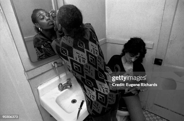 View of two people in the bathroom of an apartment in the Red Hook Houses, Brooklyn, New York, New York, April 1988. One examines her eye in the...