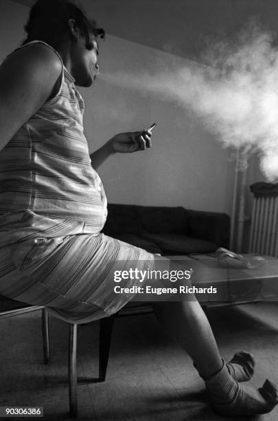 Profile of a pregnant woman smokes crack at the Red Hook Houses, Brooklyn, New York, New York, April 1988. The woman, a mother to one child, is...