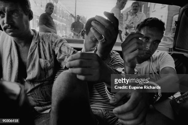 View of three man, all suspected of dealing drugs, handcuffed in the back seat of a police car, North Philadelphia, Pennsylvania, August 1989. The...