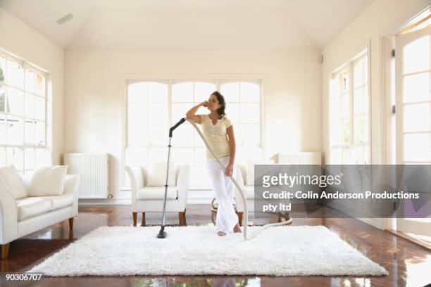 hispanic woman vacuuming floor - minimal effort stock pictures, royalty-free photos & images