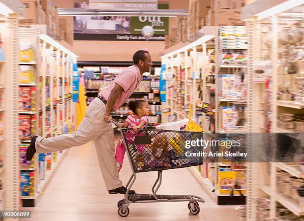 african father pushing daughter in grocery cart - carrito de la compra fotografías e imágenes de stock